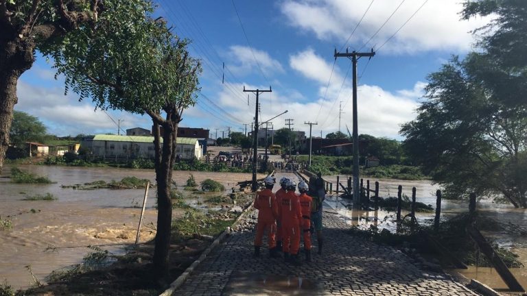 Bombeiros de um lado da ponte e moradores de Coronel João Sá, de outro, quando a água tomava a ponte na manhã deste sábado (13) — Foto: Alan Tiago/G1